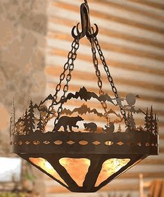 a light hanging from the ceiling with animals and trees on it's chain,