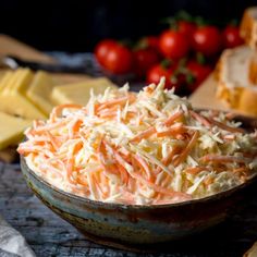 a bowl filled with coleslaw next to sliced cheese