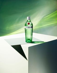 a green bottle sitting on top of a white table next to a blurry background