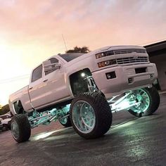 a white truck parked in a parking lot next to a building at night with its lights on