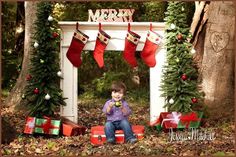 a little boy sitting in front of a christmas arch