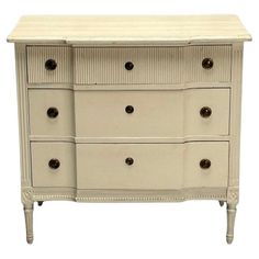 a white dresser with drawers and knobs on it's sides, against a white background