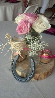 some flowers are sitting on top of a wooden block with a horseshoe and mason jar