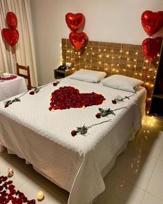 a bed with rose petals on it in a room decorated for valentine's day