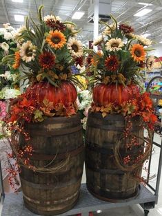 two wooden barrels with pumpkins and sunflowers on them sitting in a store