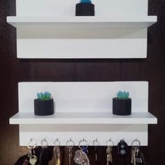 three white shelves with key holders and plants on them