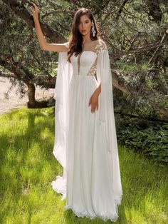 a woman in a white dress is standing under a tree and posing for the camera