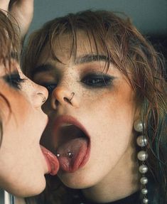 two women with their mouths open and one is sticking out her tongue to the other