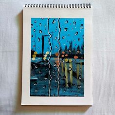 a notebook with an image of rain on the window and street lights in the background