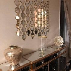 a living room filled with furniture next to a wall mounted mirror and gold vases