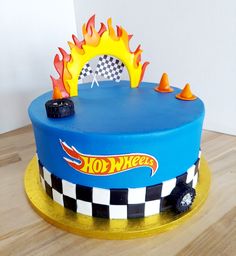 a blue cake with flames and checkered design on it's sides is sitting on a wooden table