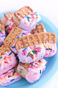 a blue plate topped with waffles covered in frosting and sprinkles