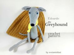 a crocheted gray dog sitting on top of a white table next to a yellow blanket