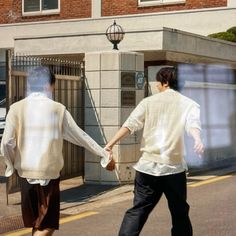 two men walking down the street holding hands