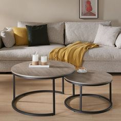 two coffee tables sitting on top of a wooden floor next to a couch and table