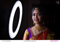 a woman in a yellow and red sari standing next to a round light fixture