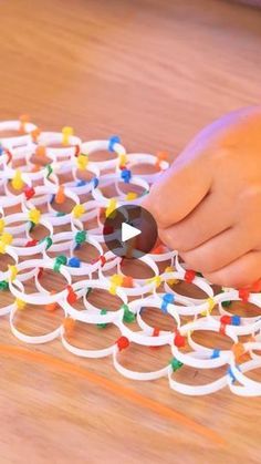 a child is playing with an interactive toy on the floor and it looks like they are making something out of plastic beads