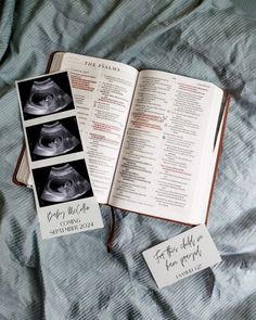 an open book sitting on top of a bed next to two cards with pictures of the same person