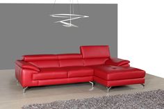 a red leather sectional sofa sitting on top of a carpeted floor in front of a gray wall