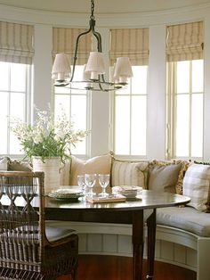 a dining room table with two chairs and a bench in front of the bay window