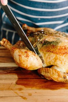 a person cutting up a chicken with a knife