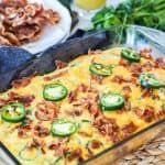 a casserole dish with bacon, jalapenos and other toppings