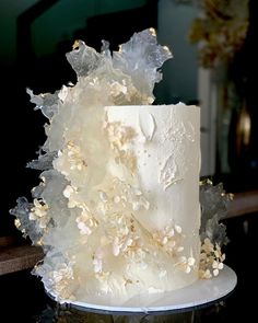 a wedding cake with white frosting and flowers on the top is sitting on a table