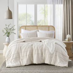 a bed with white linens and pillows in a room next to a wicker headboard