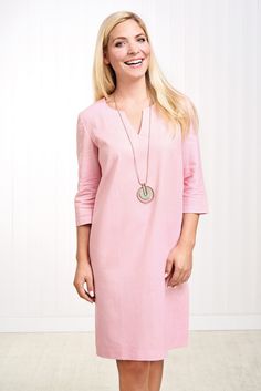 a woman in a pink dress is smiling and standing with her hands on her hips