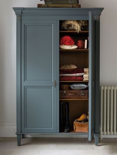 an armoire with many items in it next to a heater and radiator