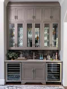 a kitchen with gray cabinets and marble counter tops, an area rug on the floor