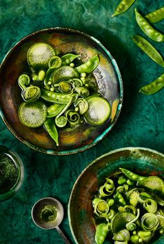 two bowls filled with green vegetables on top of a table