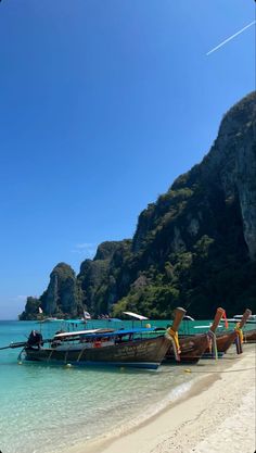 several boats are docked on the beach with clear blue water