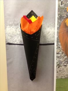 there is a paper cone with an orange and yellow flower in it on the wall