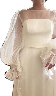 a woman wearing a white dress with sheer sleeves