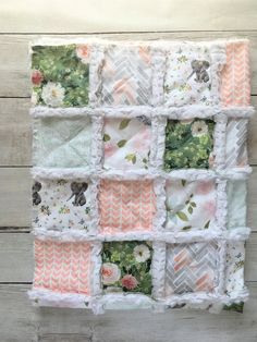 a quilted wall hanging made out of many different fabric squares and flowers on white wood planks