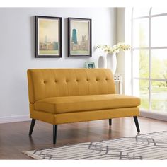 a yellow couch sitting on top of a hard wood floor next to a white rug