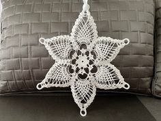 a white crocheted snowflake hanging from a pillow