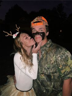 a man and woman are dressed up as deer antlers, one is kissing the other's cheek