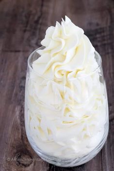 a glass filled with whipped cream on top of a wooden table