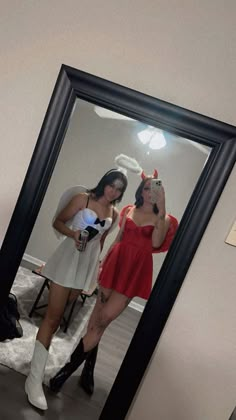 two women standing in front of a mirror with one taking a selfie and the other holding a camera