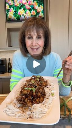 a woman sitting at a table in front of a plate of food with chopsticks