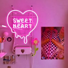 a pink neon sign that says sweet heart hangs on the wall next to a bed