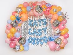 a wreath made out of balloons with the words kate's last biscuit on it