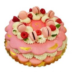 a pink and white cake topped with raspberries and other toppings on a plate