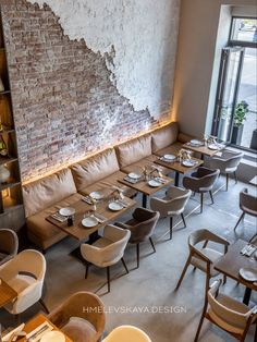 an empty restaurant with tables and chairs in front of a brick wall that has peeling paint on it