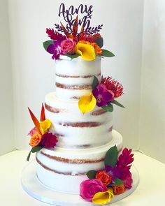 a three tiered cake with flowers on the side and a sign that says love is in the air