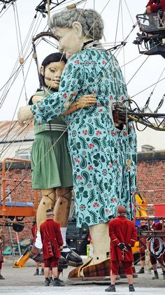 two people standing next to each other in front of a large statue that looks like a ship