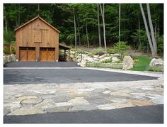 an empty parking lot in front of a wooden barn with two garage doors on each side