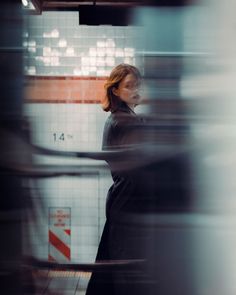 a woman standing in front of a tiled wall